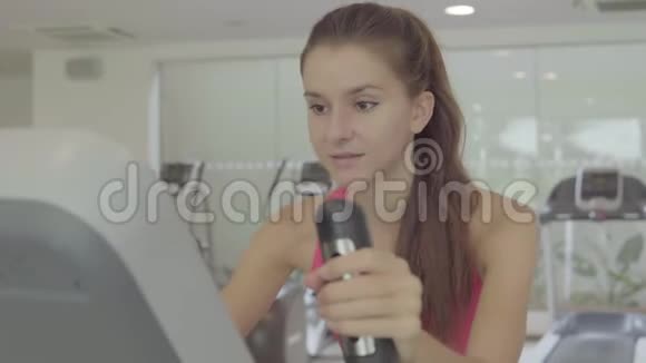 女人在健身房骑自行车锻炼腿做有氧训练骑自行车视频的预览图