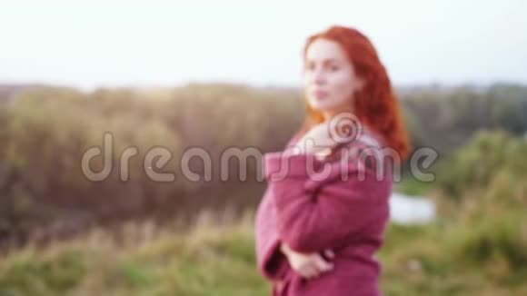 漂亮的红头发年轻女子在日落时在田野里摆姿势慢动作3840x2160视频的预览图