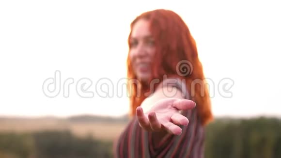 漂亮的红头发的玉容女人走在大自然的田野上用手招手跟随我的概念慢动作3840x2160视频的预览图