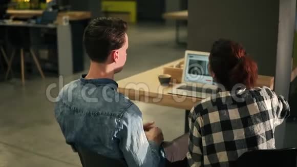 一对夫妇坐在一个光线充足的室内空间使用笔记本电脑的背面镜头上网看一些视频视频的预览图