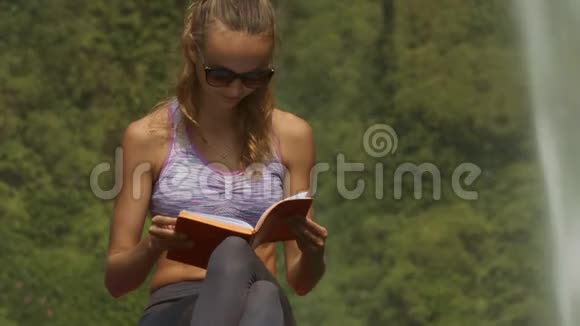 紫色上衣的女士在大石头上读日记视频的预览图