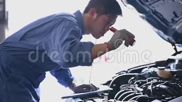 年轻的亚洲汽车机械师在汽车修理车间的汽车引擎盖检查发动机维修人员检查客户安全视频的预览图