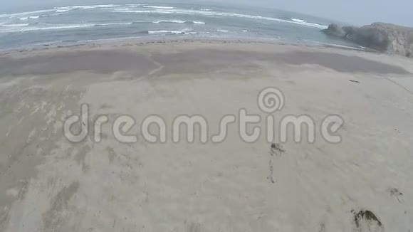 驾驶飞机飞越沙滩飞向海浪和岩石视频的预览图