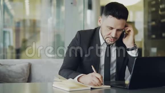 集中的高加索商人坐着在他的智能手机上交谈在他的手机上写下商业信息视频的预览图