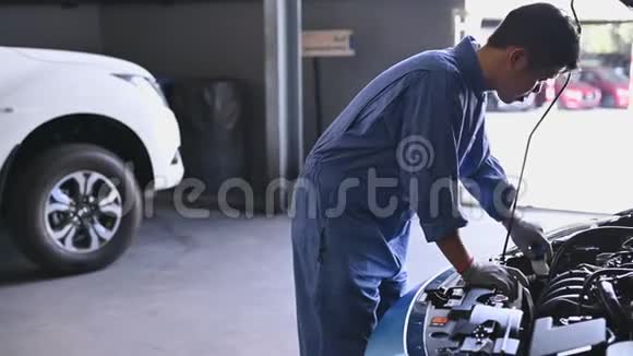 年轻的亚洲汽车机械师在汽车修理车间的汽车引擎盖检查发动机维修人员检查客户安全视频的预览图