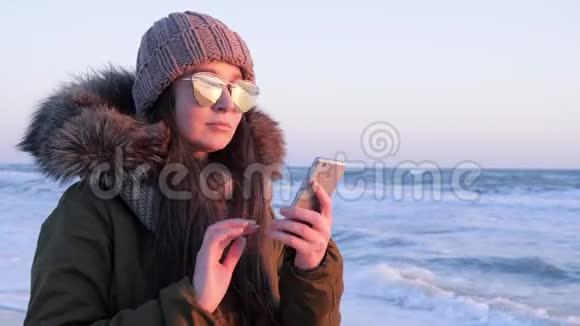 戴墨镜的女性在海上度假时在露天使用手机聊天视频的预览图