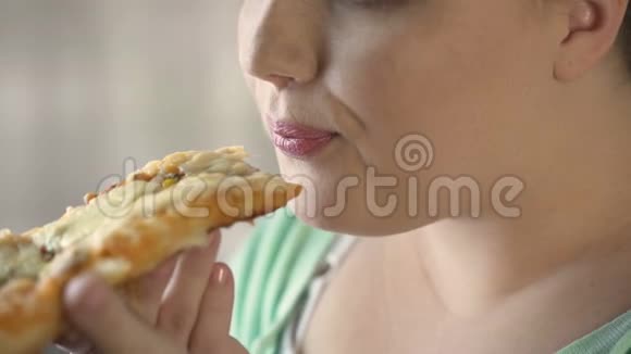 胖乎乎的女人在吃饭前吃热比萨饼吃快餐和肥胖视频的预览图
