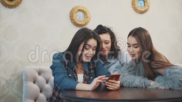 三个年轻的好女孩坐在咖啡馆里花时间交流视频的预览图