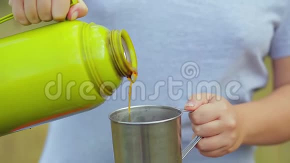女人手把热水瓶里的热茶倒进杯子里视频的预览图