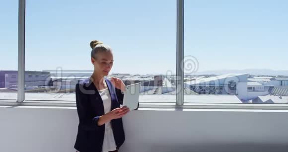 一位戴着数码平板电脑的女商人站在4K4K窗口附近视频的预览图