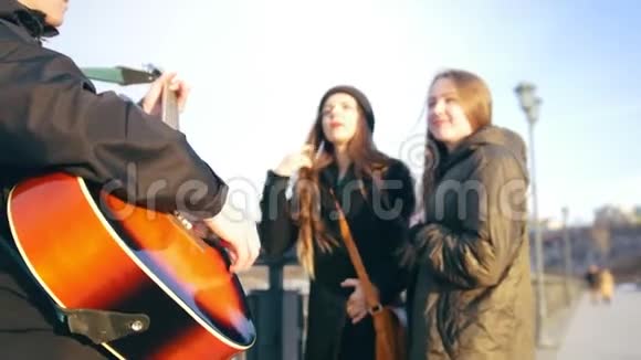 年轻女孩玩得开心而男人在户外弹吉他视频的预览图