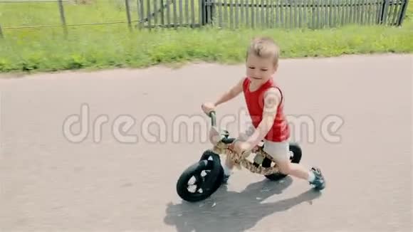 一个穿红色T恤的小男孩骑着一辆跑步自行车视频的预览图