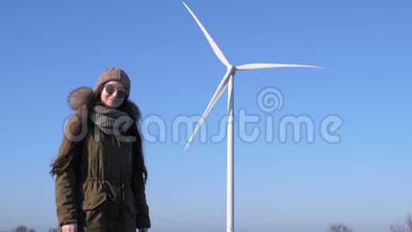 风力发电机戴眼镜的长发女孩在空中的风车上展示手指视频的预览图