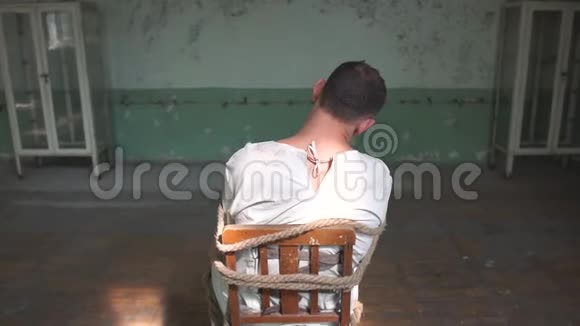 一个疯子坐在破旧房间的椅子上视频的预览图