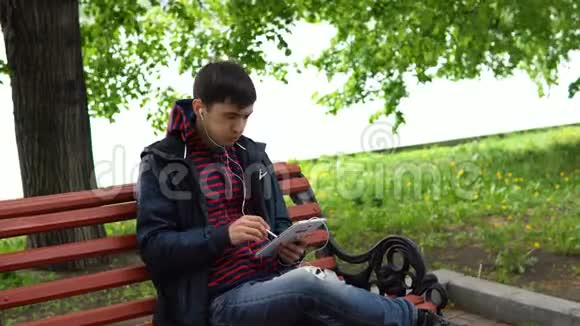 一个人在公园里听音乐和使用平板电脑视频的预览图
