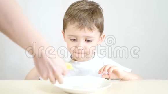 孩子很高兴地吃了他母亲给他的薯片一个孩子坐在白色的桌子旁视频的预览图