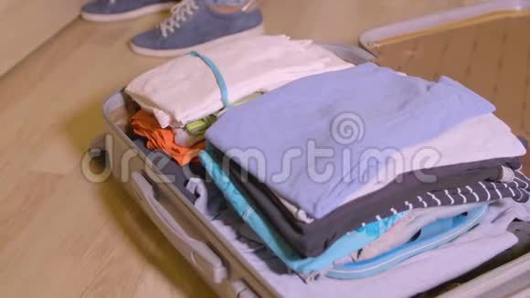 女人把东西和衣服放在旅行箱里放在家里的地板上视频的预览图