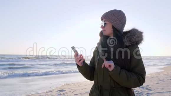 在网上聊天女性在度假时坐在使用海上智能手机的社交网络中视频的预览图