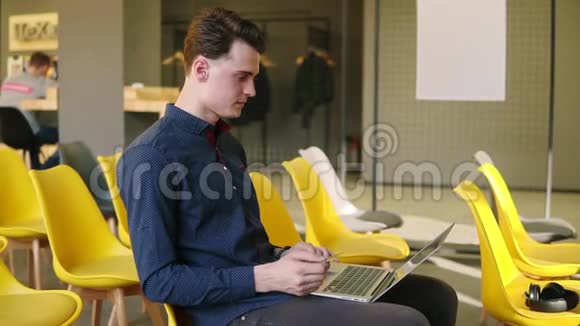 年轻有魅力的家伙正在使用设备在笔记本电脑上工作共同工作空间视频的预览图