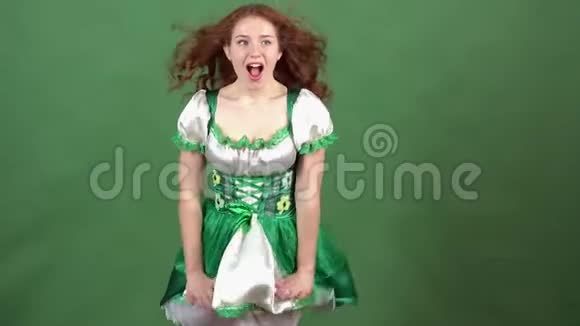 庆祝圣帕特里克节的年轻女子穿着传统的裙子绿色的墙上传递空气亲吻视频的预览图
