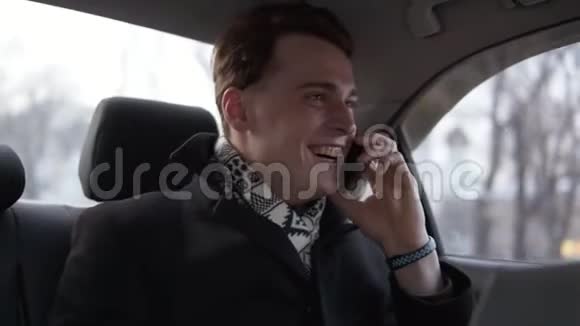 穿着黑色时髦外套的帅哥在和车里的人打电话时微笑着视频的预览图