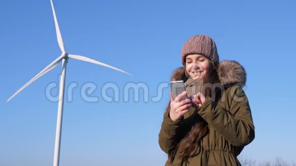 上网聊天漂亮的女性坐在风车旁用手机社交网络视频的预览图