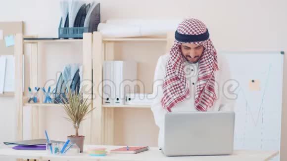 现代中东人穿着民族服装在办公桌前的办公室工作头上戴着古特拉的商人视频的预览图