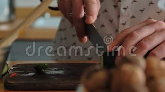雄性手把黄瓜切成黑色木切割板上的环视频的预览图