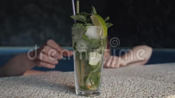 女孩喝含酒精的莫吉托饮料与薄荷和石灰一杯莫吉托杯的特写视频的预览图