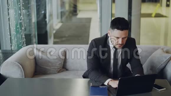 受人尊敬的白人商人穿着黑色商务服坐着工作专注于现代的笔记本电脑视频的预览图