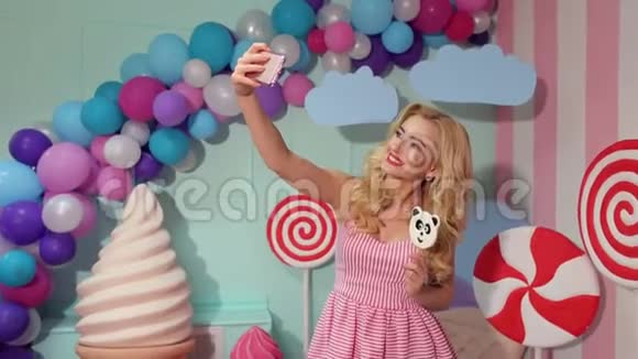 穿粉色连衣裙的女孩用大棒棒糖做自拍视频的预览图