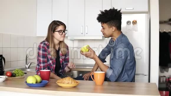 可爱的夫妇一起吃苹果坐在宽敞明亮的舒适厨房里视频的预览图