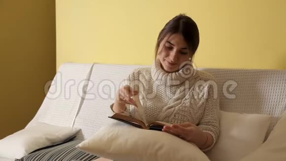 一个年轻的女孩穿着舒适温暖的毛衣在冬天的晚上在家看书睡觉视频的预览图