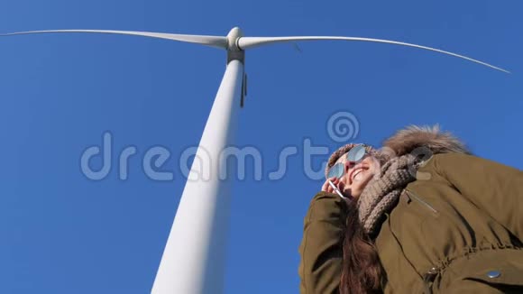 现代科技戴墨镜的女性站在风车下对着蓝天说话视频的预览图