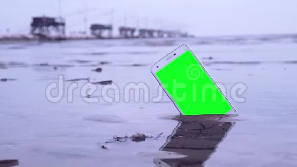 沙滩上有绿色屏幕的智能手机视频的预览图