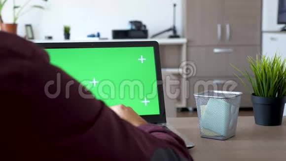 在笔记本电脑上工作的人的后拍上面有绿色屏幕视频的预览图