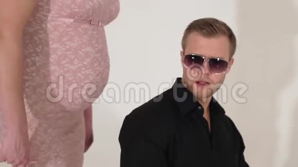 穿西装戴墨镜的帅哥在穿粉色衣服的怀孕女孩旁边唱歌视频的预览图