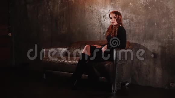 漂亮的苗条女人坐在黑暗的房间里两腿交叉调情视频的预览图