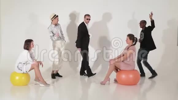 跳舞成熟有魅力的男人和坐在大球上的可爱女人视频的预览图