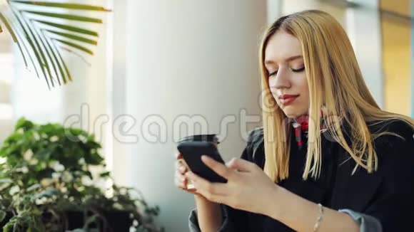 坐在咖啡馆里的女青年在她的智能手机里键入一些东西视频的预览图