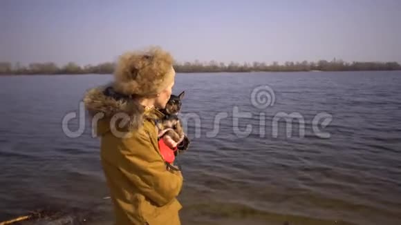 一位成年金发卷发白人妇女的肖像她手里拿着一只黑色的小狗种玩具猎犬老搞笑视频的预览图