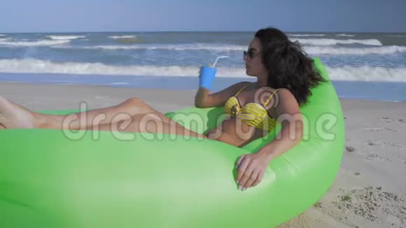 阳光下美丽的女人在海边休息喝一杯鸡尾酒视频的预览图