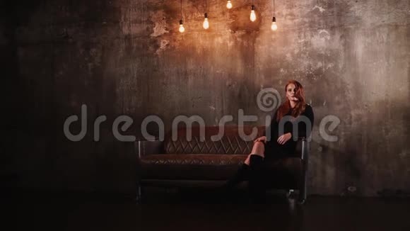迷人的年轻女子正躺在黑暗的空房间里的沙发上视频的预览图