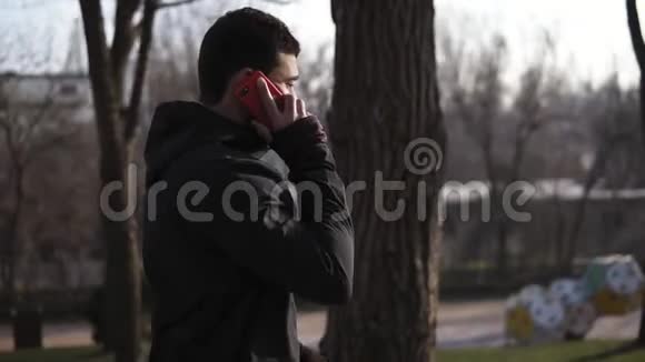 无法辨认的男性在公园里散步在电话里和别人说话视频的预览图