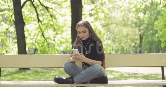 温柔的女人在长凳上带电话视频的预览图