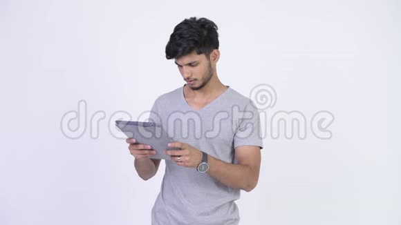 年轻快乐留胡子的印度男人使用数码平板电脑得到好消息视频的预览图