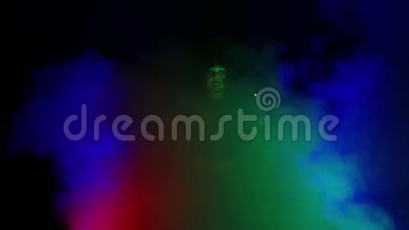 一个年轻的女巫在灯光下在烟雾云中黑色手里拿着蜡烛从事魔法视频的预览图