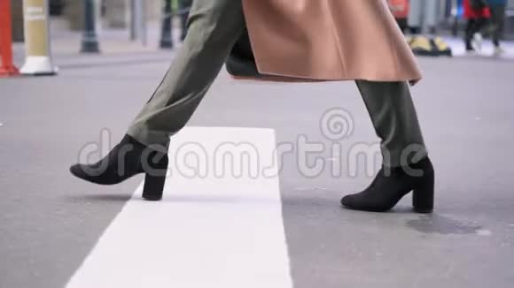 穿黑色靴子的女人的腿穿过马路视频的预览图