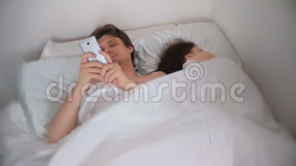 丈夫正在看手机里的东西而他的妻子正在睡觉视频的预览图