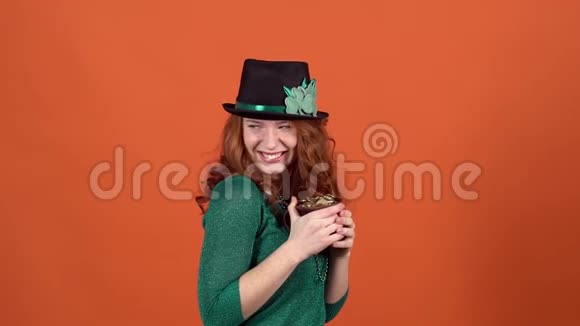 庆祝圣帕特里克节的年轻女子戴着帽子的橙色墙视频的预览图